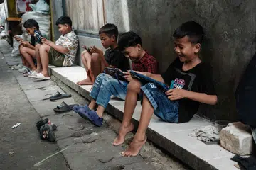 Kanak-kanak bermain permainan dalam talian menggunakan telefon bijak dan tablet di sebuah lorong di Jakarta pada 26 Mac 2026. Kesatuan Eropah (EU) dijangka mengemukakan cadangan bagi membendung ciri media sosial yang boleh menyebabkan ketagihan dalam kalangan kanak-kanak dan remaja, ketika semakin banyak negara mengambil langkah mengehadkan akses golongan bawah umur kepada platform berkenaan.