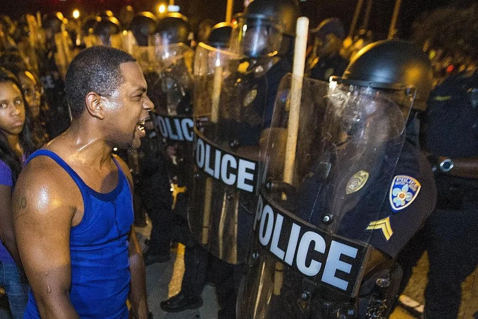 HUBUNGAN KAUM SEMAKIN TEGANG: Seorang penduduk kulit hitam berdepan dengan polis perusuh di bandar Baton Rouge, Lousiana, semalam, dalam satu bantahan menentang tindakan polis menembak mati dua lelaki kulit hitam di Texas baru-baru ini. - Foto AFP