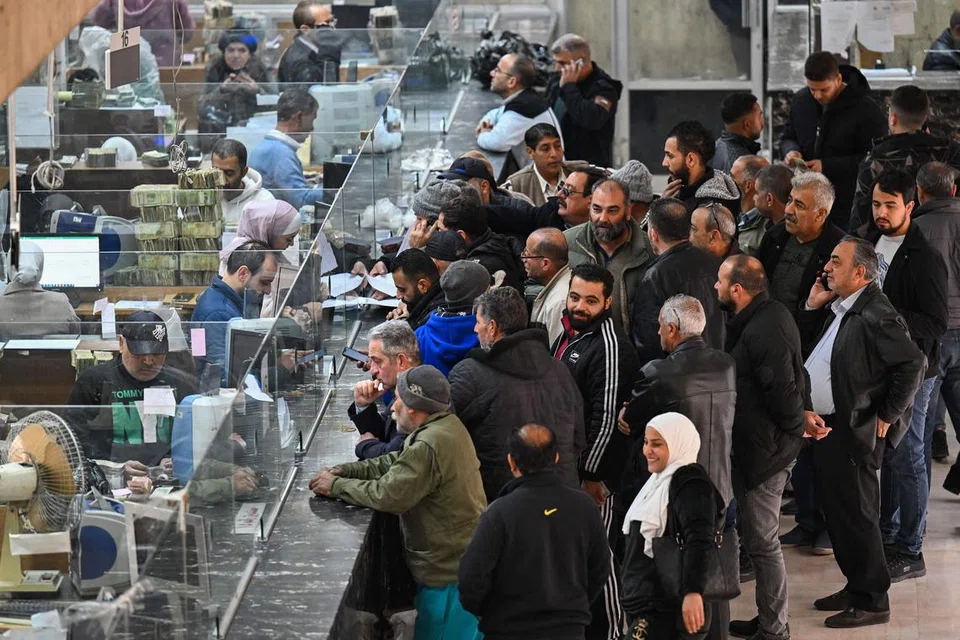 Orang ramai beratur di hadapan kaunter di sebuah bank komersial yang mempunyai pertalian dengan bank pusat Syria di Damsyik pada 16 Disember 2024.