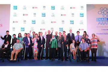 DIIKTIRAF: Presiden Halimah (berbaju hijau) dan Menteri Kanan Emeritus (ESM) Goh Chok Tong (sebelahnya) bersama 13 individu kurang upaya yang diiktiraf dengan Anugerah Enable Goh Chok Tong atas pencapaian luar biasa mereka dan potensi mereka dalam bidang masing-masing. - Foto BH oleh ONG WEE JIN