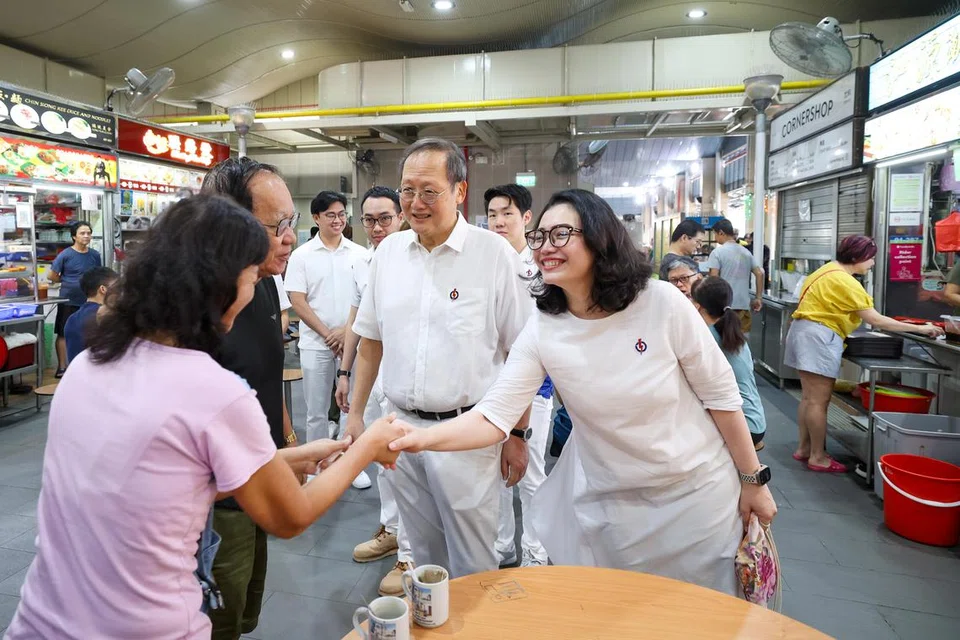 Cik Hazlina Abdul Halim (kanan) bersalaman dengan pelanggan semasa lawatan ke 50A Pasar Marine Terrace pada 22 Mac. Menteri Tenaga Manusia, Dr Tan See Leng (tengah),  memperkenalkannya sebagai wajah baru PAP.