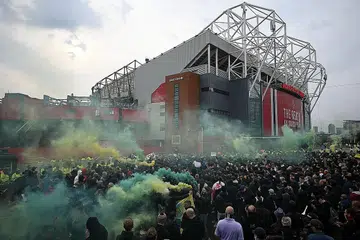 BANTAHAN LAGI: Para penyokong United sekali lagi mengadakan bantahan di luar Old Trafford sebelum perlawanan menentang Liverpool semalam. Perlawanan antara kedua-dua kelab itu telah ditangguhkan setelah peminat membuat bantahan yang turut menyaksikan mereka memasuki padang. - Foto AFP
