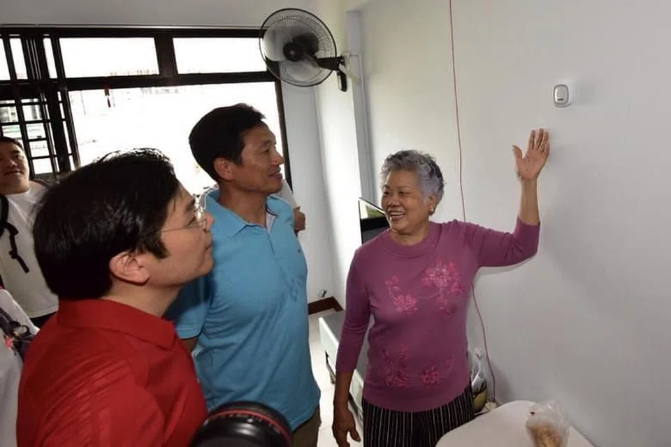 Dari kiri: Menteri Pembangunan Negara, Lawrence Wong dan Menteri Pelajaran Ong Ye Kung dengan Cik Teng Ah Moi yang menunjukkan ciri-ciri keselamatan di dalam flatnya, semasa lawatan menteri ke Jurong Central, pada 15 Julai 2018. 