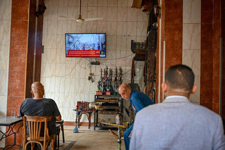 DETIK CEMAS: Pelanggan di sebuah kafe kecil di Kahirah terpaku menonton laporan berita di televisyen mengenai konflik pada 11 November. 