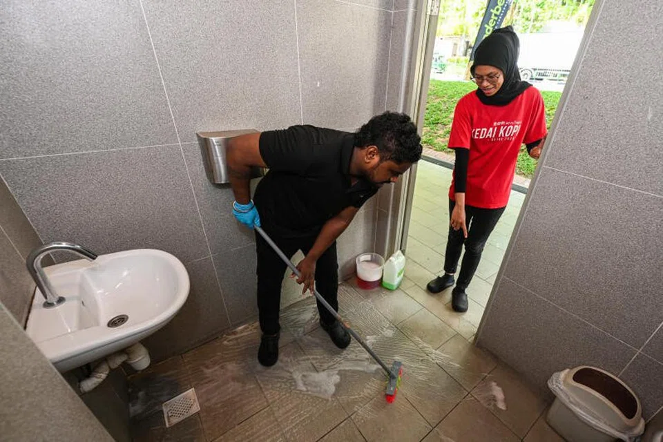 Penyelia pembersihan Kedai Kopi, Cik Nurmaisarah Sofea Aziz (kanan, berbaju merah) kerap melakukan pemeriksaan ringkas sepanjang hari bagi memastikan agar tandas di kedai kopi, Kedai. Kopi, tidak kotor.