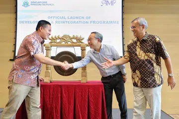 Encik Amrin berjabat tangan dengan Pesuruhjaya Penjara Desmond Chin, dengan disaksikan Pengarah Eksekutif AMP Encik Mohd Anuar Yusop, di pelancaran program pada Sabtu (17 November).