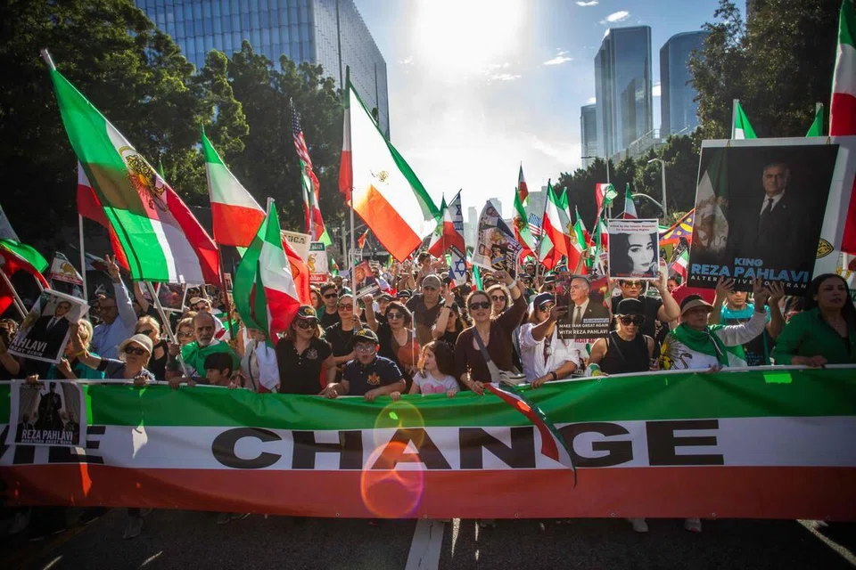 Rakyat Iran dan para penyokong memegang sepanduk serta bendera Iran era pra-rejim semasa acara “Solidariti Bersama Rakyat Iran” di hadapan Dewan Bandaraya di pusat bandar Los Angeles pada 18 Januari 2026. Ribuan penunjuk perasaan berhimpun di Los Angeles bagi membantah tindakan keras pemerintah Iran terhadap bantahan awam.