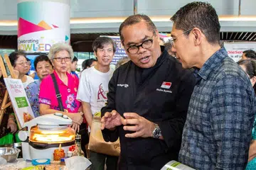 KONGSI TIPS MAKANAN SIHAT: Konsultan Makanan Cef Mazlan Boyamin (berbaju hitam) dari Persekutuan Kulinari Halal Singapura (SHCF) berkongsi ilmu tentang makanan sihat dengan Menteri Negara Kanan (Pertahanan merangkap Ehwal Luar), Dr Mohamad Maliki Osman (kanan) yang juga Mayor Majlis Pembangunan Masyarakat (CDC) South East. Cef Mazlan mengendali beberapa kursus pemakanan dalam siri Shiok Persatuan Rakyat (PA). - Foto BH oleh ZALEHA ABDUL KADER