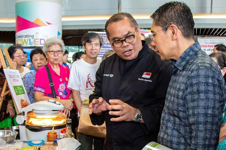 KONGSI TIPS MAKANAN SIHAT: Konsultan Makanan Cef Mazlan Boyamin (berbaju hitam) dari Persekutuan Kulinari Halal Singapura (SHCF) berkongsi ilmu tentang makanan sihat dengan Menteri Negara Kanan (Pertahanan merangkap Ehwal Luar), Dr Mohamad Maliki Osman (kanan) yang juga Mayor Majlis Pembangunan Masyarakat (CDC) South East. Cef Mazlan mengendali beberapa kursus pemakanan dalam siri Shiok Persatuan Rakyat (PA). - Foto BH oleh ZALEHA ABDUL KADER