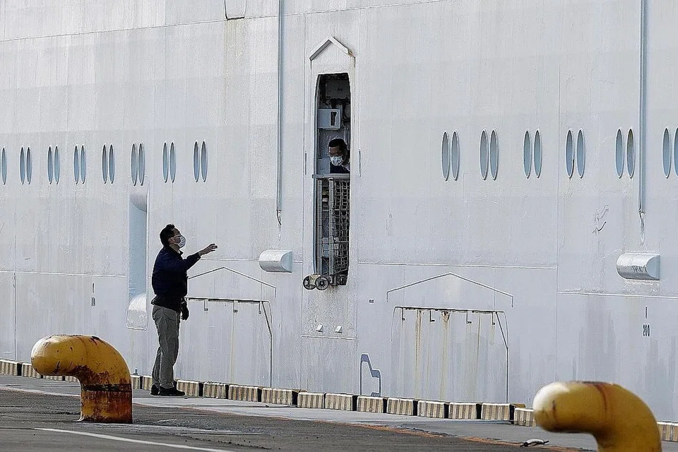 TIDAK DAPAT LARI: Seorang pekerja pelabuhan (kiri) bercakap dengan seorang anak kapal selepas kapal persiaran Diamond Princess, tempat 10 individu disahkan dijangkiti koronavirus, berlabuh di Yokohama, Jepun, pada 6 Februari lalu.