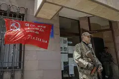 OFENSIF RUSSIA: Seorang anggota militia Republik Rakyat Donetsk mengawal pintu masuk bangunan pentadbiran bandar Svitlodarsk, di wilayah Donetsk (gambar atas), Khamis lalu. Tentera Russia menawan Svetlodarsk, yang terletak 80 km ke barat laut Severodonetsk. Sementara itu, mereka terus membedil kawasan dekat Novomykhailivka dalam usaha untuk menguasai wilayah Donetsk. - Foto-foto REUTERS