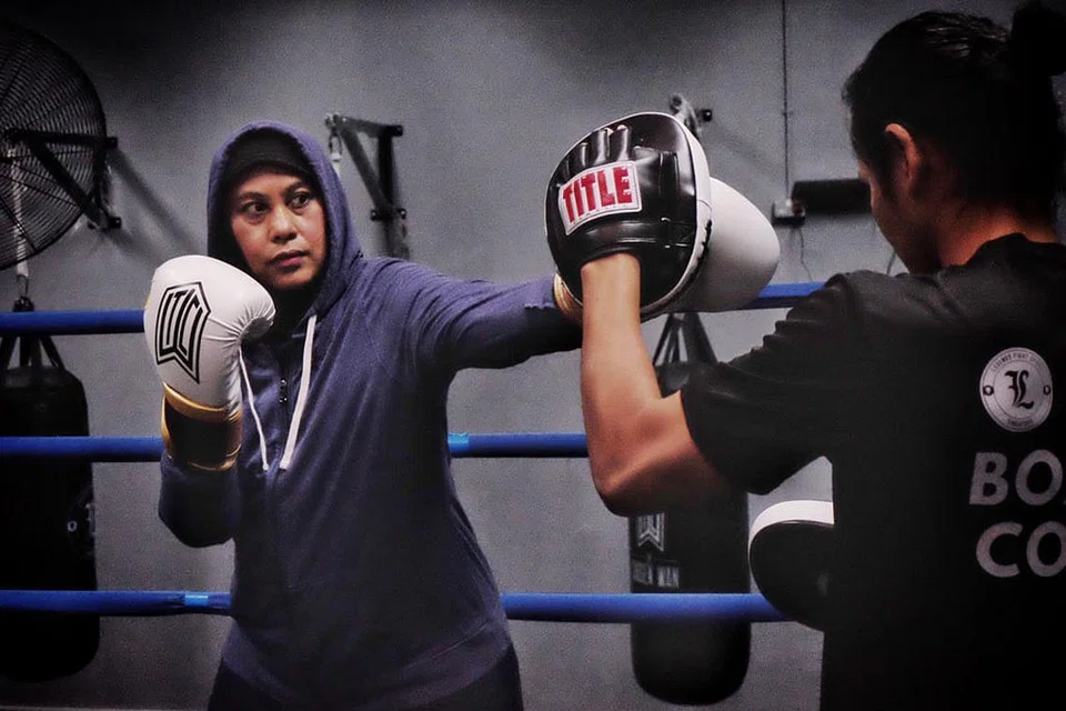 LATIHAN BERTERUSAN: Pengacara 'The BM Show', Hanim Mohd Saleh, mendapat bimbingan teknik bertinju daripada Muhamad Ridhwan Ahmad di gimnasium Legends Fight Sport cawangan Tampines, sukan yang dianggapnya tetap menarik minat orang ramai, bahkan kini menerima semakin ramai pelatih wanita yang mahu belajar bertinju.- Foto BM oleh KHALID BABA