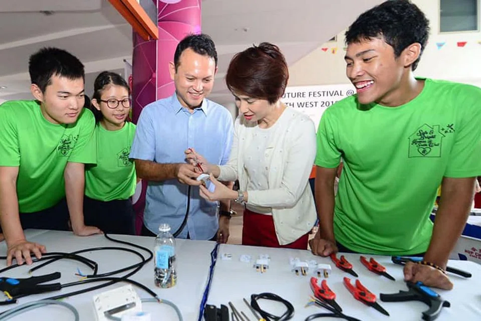 TINGKAT KEMAHIRAN: Menteri Negara (Tenaga Manusia merangkap Pembangunan Negara), Encik Zaqy Mohamad (tiga dari kiri) dan Mayor CDC South West, Cik Low Yen Ling (dua dari kanan), mempelajari cara 'membaiki' palam daripada relawan Institut Pendidikan Teknikal (ITE) Kolej Barat di acara Pesta SkillsFuture@South West di Kelab Masyarakat Keat Hong. - Foto FACEBOOK CDC SOUTH WEST