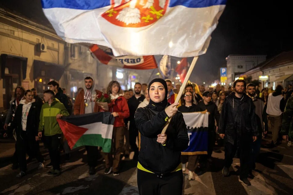 Pelajar Merima Avdic dari Novi Pazar mengibarkan bendera Serbia ketika disambut penduduk tempatan dalam perjalanannya menuju ke Novi Sad, semasa perarakan protes susulan tragedi runtuhan kanopi stesen kereta api Novi Sad pada November 2024 yang mengorbankan 16 nyawa dan mencetuskan tuduhan meluas terhadap rasuah serta kecuaian kerajaan, 27 Oktober 2025. Sekatan selama setahun oleh pelajar di Universiti Novi Pazar, yang menghentikan kuliah, berakhir lebih seminggu lalu selepas rektor universiti digantikan dan larangan terhadap 200 pelajar yang dipecat kerana aktivisme anti-kerajaan ditarik balik. Protes itu berlanjutan lebih lama berbanding kebanyakan universiti lain di Serbia, termasuk pendudukan bangunan walaupun pihak berkuasa memutuskan bekalan pemanas.