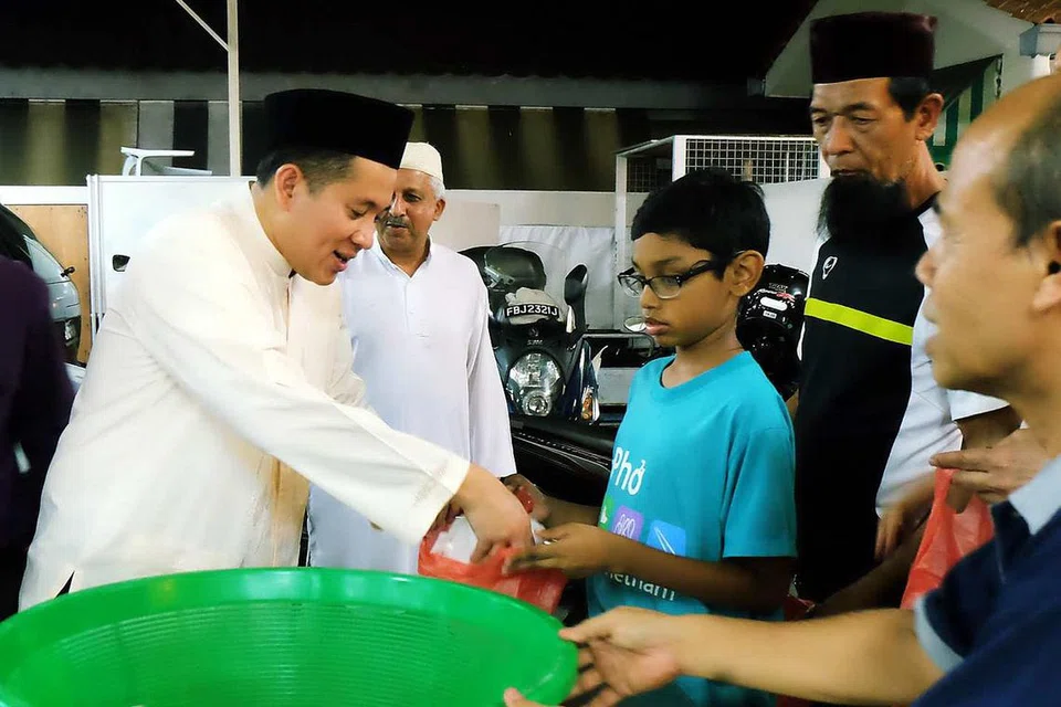 BANTU AGIH BERIANI KEPADA JEMAAH: Encik Amrin Amin (kiri) sedang membantu mengagihkan nasi beriani kepada jemaah di Masjid Khalid bersama beberapa sukarelawan. - Foto KHALID BABA