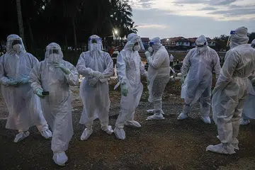 BUKAN LANGKAH MENYERAMKAN, TAPI KESELAMATAN: Pekerja kesihatan yang ditugaskan menguruskan pengebumian mangsa Covid-19 mengenakan pakaian hazmat serba putih sewaktu urusan pengebumian di Kuala Selangor Isnin lalu. - Foto EPA-EFE