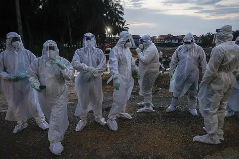 BUKAN LANGKAH MENYERAMKAN, TAPI KESELAMATAN: Pekerja kesihatan yang ditugaskan menguruskan pengebumian mangsa Covid-19 mengenakan pakaian hazmat serba putih sewaktu urusan pengebumian di Kuala Selangor Isnin lalu. - Foto EPA-EFE