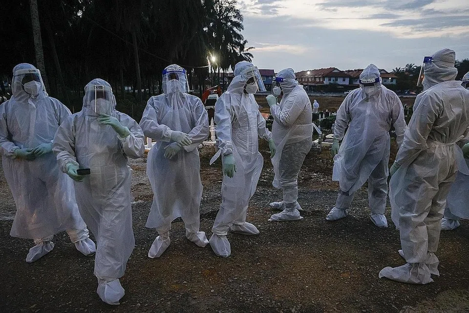 BUKAN LANGKAH MENYERAMKAN, TAPI KESELAMATAN: Pekerja kesihatan yang ditugaskan menguruskan pengebumian mangsa Covid-19 mengenakan pakaian hazmat serba putih sewaktu urusan pengebumian di Kuala Selangor Isnin lalu. - Foto EPA-EFE