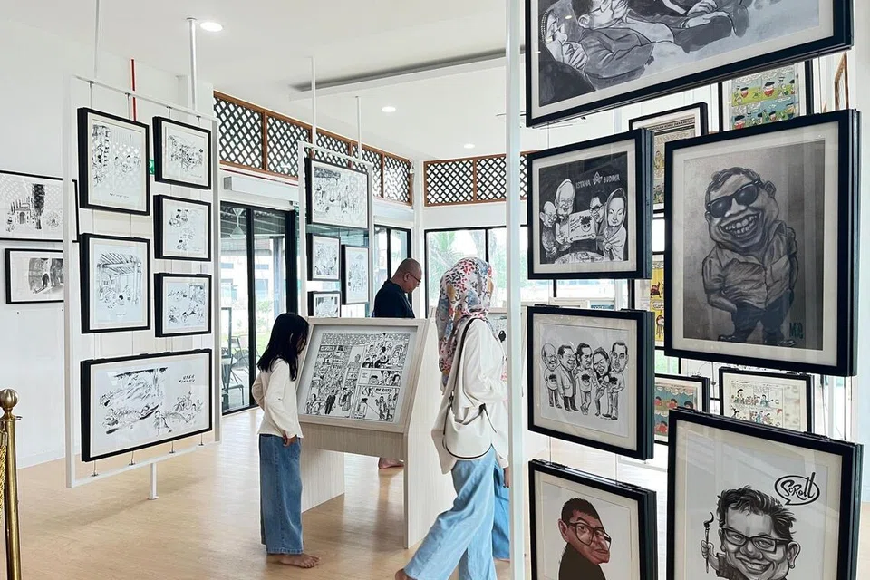 Pengunjung leka meneliti lukisan kartun karya Datuk Lat yang dipamerkan di Galeri Rumah Lat di Batu Gajah, Perak. 