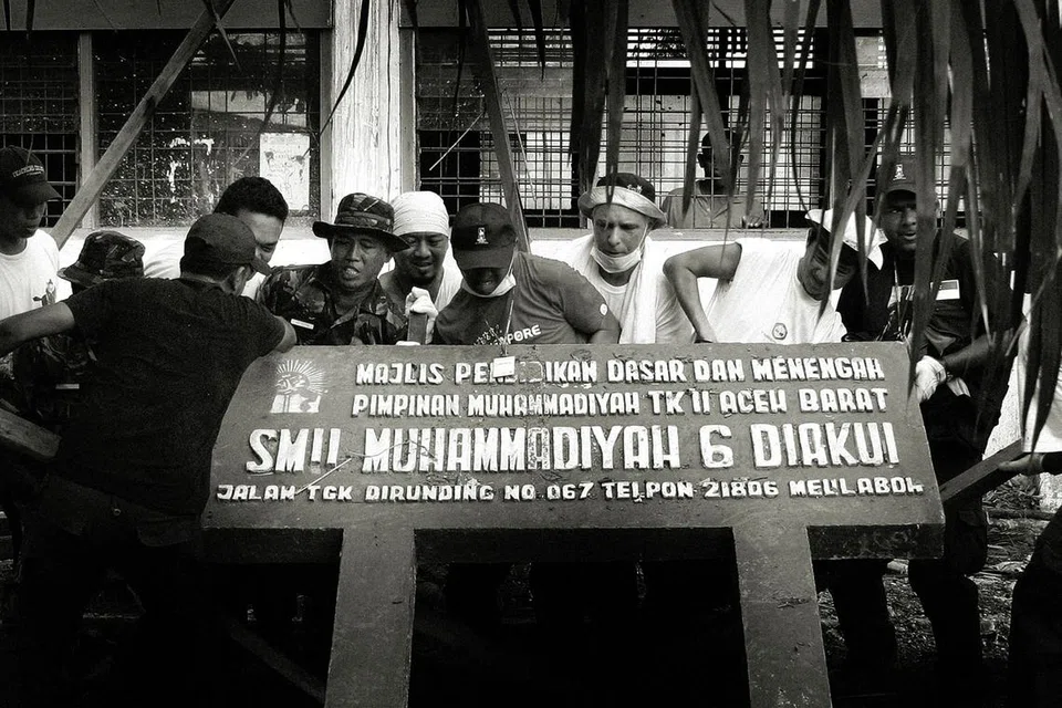 Sukarelawan Mercy Relief dan tentera Indonesia memasang papan tanda Sekolah Muhammadiyah seberat 226.8 kilogram di Simpang Temasek.