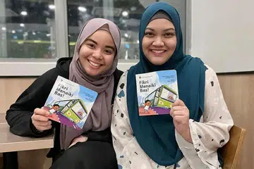 KARYA KREATIF UNTUK SI KECIL: Dua mantan penuntut NIE, Cik Nurul Syafiqah Anuar Khan (kiri) dan Cik Farah Adibah Johari, menghasilkan buku Fikri Menaiki Bas! untuk galak kanak-kanak mesra dengan bahasa Melayu.- Foto ihsan NURUL SYAFIQAH