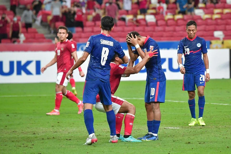 Penyerang Singapura, Faris Ramli (dua dari kanan) didekati bek kanan Indonesia, Asnawi Mangkualam (tengah) yang cuba ‘memujuk’nya selepas beliau gagal menyempurnakan penalti pada masa kecederaan separuh masa kedua untuk memberikan kemenangan kepada Singapura di Stadium Nasional pada 25 Disember 2021. Indonesia menang 4-2 selepas masa tambahan dengan agregat 5-3.