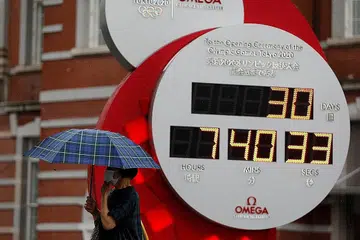 MENUNGGU MASA: Seorang wanita berpelitup kelihatan berjalan di sebelah sebuah jam yang menunjukkan tempoh ketibaan pelancaran Sukan Olimpik Tokyo dalam masa 30 hari lagi mulai 23 Julai, lengkap dengan jam, minit dan saatnya. - Foto REUTERS