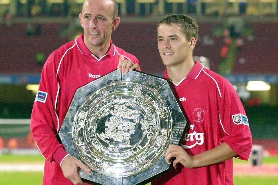 RANGKUL PIALA: Bekas pemain Liverpool Gary McAllister (kiri) and Michael Owen meraikan kejayaan dalam Piala Sumbangsih setelah mengalahkan Manchester United 2-1 pada 2001.