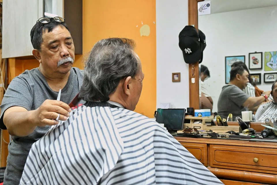 Encik Hamzah menggunting rambut pelanggan setia, Encik Abdul Kadir, yang sudah mengunjungi kedai gunting, Bugs Bunny, selama lebih 20 tahun.