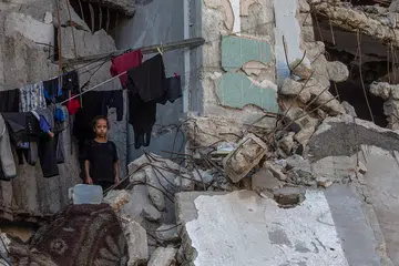 Seorang kanak-kanak perempuan Palestin yang kehilangan tempat tinggal berdiri di sebelah pakaian yang disidai di dalam sebuah bangunan yang runtuh di Bandar Gaza, Semenanjung Gaza, pada 21 September 2026. Pertubuhan Bangsa-Bangsa Bersatu (PBB) memberi amaran bahawa ratusan struktur yang rosak akibat perang di seluruh Gaza masih berisiko runtuh, walaupun ia menjadi tempat perlindungan bagi keluarga yang kehilangan tempat tinggal di tengah-tengah kekurangan tempat berteduh yang kritikal.