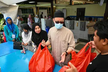 KEMBALI RANCAK: Cik Siti Hamidah Abdul Gapor (tengah, tudung hitam) mengambil tempahan daging korbannya di Masjid Petempatan Melayu Sembawang pada Khamis. 