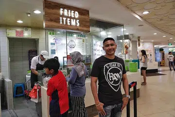 KURANGKAN KOS: Encik Ashik (atas kanan) berkata sinergi hasil pembelian NTUC Enterprise, membolehkan pegerai Kopitiam sepertinya membeli bahan makanan secara borong bagi mengurangkan kos. - Foto BM oleh KEVIN LIM