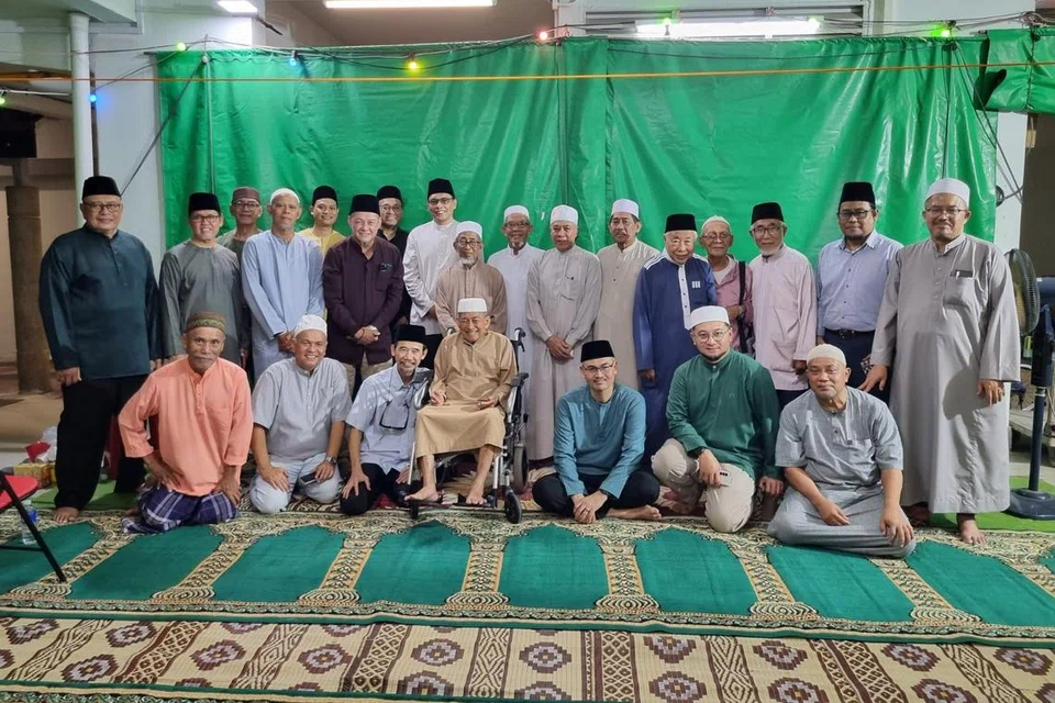 Ketua Eksekutif, Majlis Ugama Islam Singapura (Muis), Encik Kadir Maideen (berdiri, lapan dari kiri, berbaju putih) bersama Pengerusi Eksekutif Masjid Hasanah, Encik Mohd Rafi Eusope (berdiri, enam dari kiri), bersama ahli Qaryah Pandan di kolong Blok 404, Pandan Gardens, sewaktu solat tarawih 2024.  