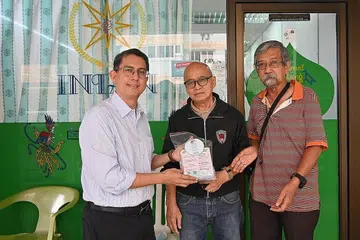MENDEKATI PERNIAGAAN KEJIRANAN: Dr Faishal (kiri) bersama salah seorang pemilik kedai gunting rambut di Jurong baru-baru ini. - Foto FACEBOOK MUHAMMAD FAISHAL IBRAHIM