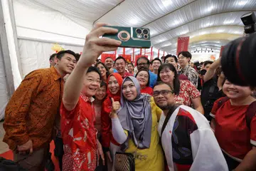 Encik Lawrence Wong   mengambil swafoto bersama tetamu semasa satu majlis Tahun Baru Cina di halaman Istana pada 25 Februari. 
