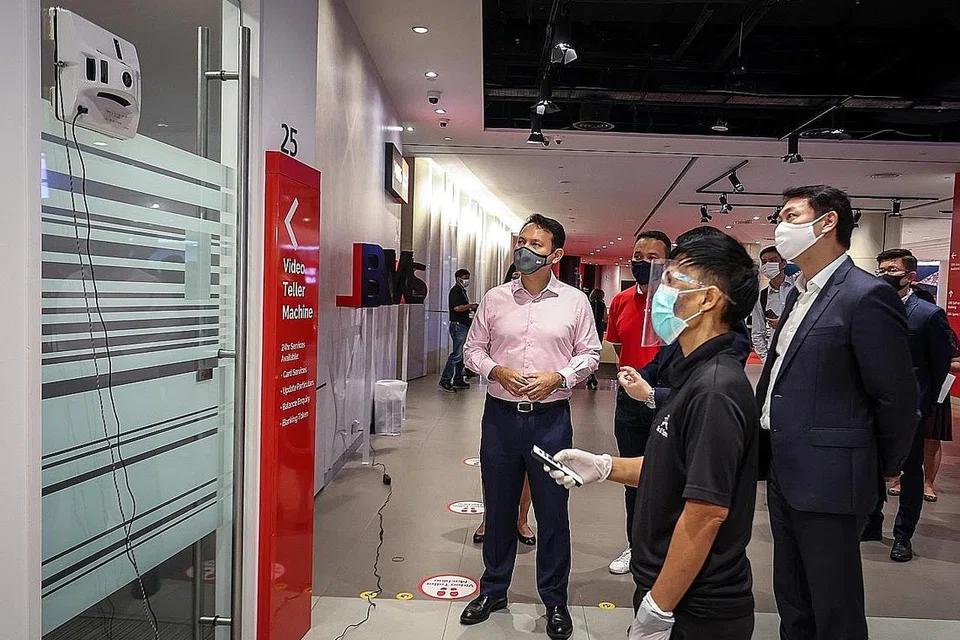 LAWATAN SYARIKAT: Encik Zaqy Mohamad (kiri) meninjau teknologi pembersihan untuk membersihkan pintu yang digunakan pekerja syarikat penyedia khidmat pembersihan Spic & Span di Pusat Kewangan DBS-Marina Bay semalam. - Foto MOM