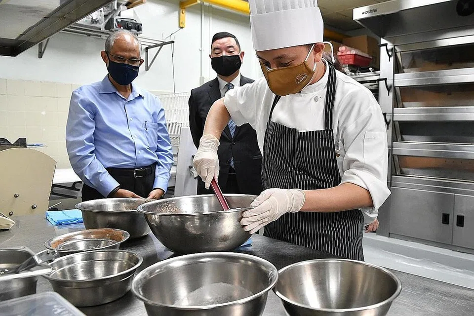 PERANAN DIHARGAI: (Dari kiri) Encik Masagos dan Pengurus Besar Parkroyal Collection Marina Bay, Encik Melvin Lim menyaksikan 'aksi' cef pastri, Encik Classen Cheong, yang merupakan salah seorang pekerja kurang upaya di hotel tersebut. - Foto BH oleh CHONG JUN LIANG