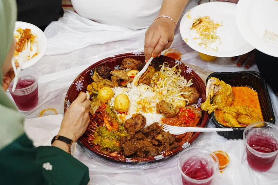 Anak-anak muda menikmati hidangan nasi ambeng dan kuih-muih tradisional di perjumpaan Hari Raya wadah digital Berita Harian, OMGxBH, di Kampong Lorong Buangkok. 