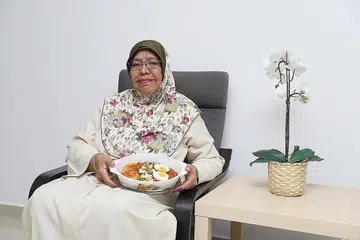 CEF KELUARGA: Cik Zaharah Ismail, 67 tahun, bersama salah satu masakan popularnya, mi siam. - Foto BM oleh MARCELLIN LOPEZ