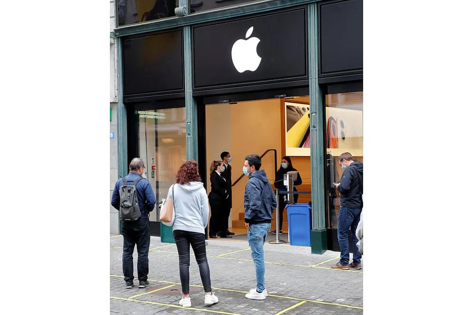 BUKA SEMULA: Kakitangan dan pelanggan Apple sedang berdiri di depan gedung Apple di Switzerland yang telah melonggarkan perintah berkurung di negara itu.- Foto REUTERS