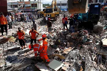 MENCARI MANGSA TERPERANGKAP: Anggota penyelamat dengan menggunakan jentera berat giat mengalihkan timbunan runtuhan untuk mencari mangsa yang terperangkap di pasar Meureudu, Pidie Jaya, Aceh, semalam. - Foto REUTERS