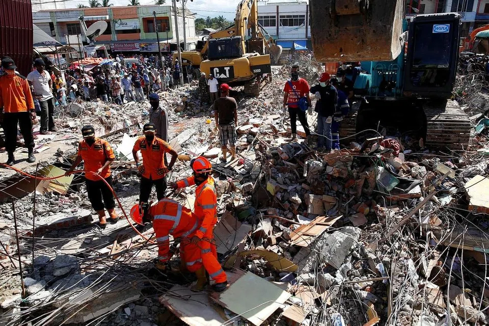 MENCARI MANGSA TERPERANGKAP: Anggota penyelamat dengan menggunakan jentera berat giat mengalihkan timbunan runtuhan untuk mencari mangsa yang terperangkap di pasar Meureudu, Pidie Jaya, Aceh, semalam. - Foto REUTERS