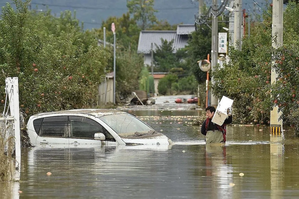 SABAR MENANTI: Seorang lelaki meredah air yang naik ekoran Taufan Hagibis di Nagano. - Foto AFP