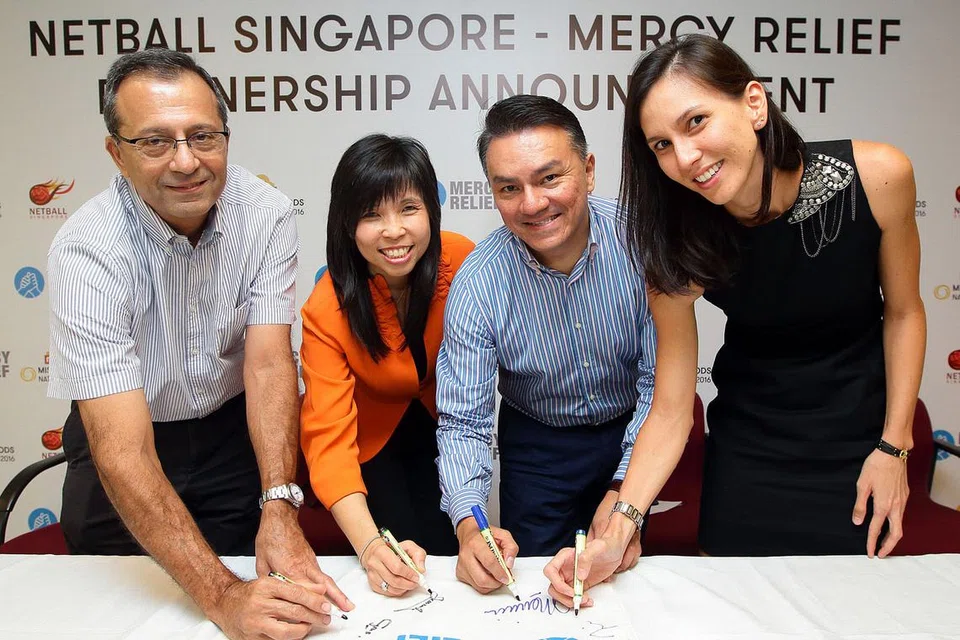 BERGANDING BARU: (Dari kiri) Ketua Pegawai Eksekutif (CEO) Netball Singapore, Cyrus Medora; Presiden Netball Singapore, Jessica Tan; Pengerusi Mercy Relief, Suhaimi Rafdi; dan Pengarah Eksekutif Mercy Relief, Zhang Tingjun; menurunkan tandatangan pada pek bantuan bencana Mercy Relief sebagai simbol perkongsian mereka. - Foto NETBALL SINGAPORE