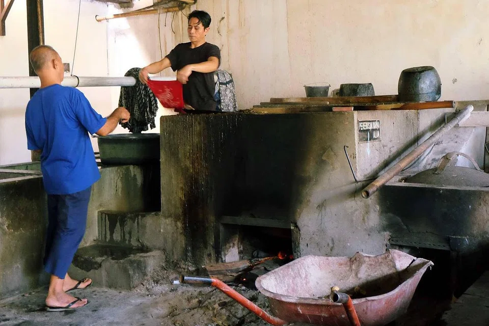 Para pekerja memproses teknik pewarnaan tahan lilin Indonesia yang digunakan pada keseluruhan kain. Teknik ini berasal dari pulau Jawa, Indonesia.