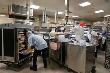 SEDIAKAN MAKANAN: (Atas) Kakitangan menyediakan makanan dan memuatkannya ke dalam troli di dapur bawah tanah Hospital Besar Singapura (SGH). Ia mengambil masa sekitar dua jam untuk menghantar makanan kepada semua pesakit pada waktu makan, yang bermula pada 6.15 pagi untuk sarapan, 10.15 pagi untuk makan tengah hari dan 4.15 petang untuk makan malam.