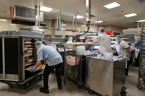 SEDIAKAN MAKANAN: (Atas) Kakitangan menyediakan makanan dan memuatkannya ke dalam troli di dapur bawah tanah Hospital Besar Singapura (SGH). Ia mengambil masa sekitar dua jam untuk menghantar makanan kepada semua pesakit pada waktu makan, yang bermula pada 6.15 pagi untuk sarapan, 10.15 pagi untuk makan tengah hari dan 4.15 petang untuk makan malam.