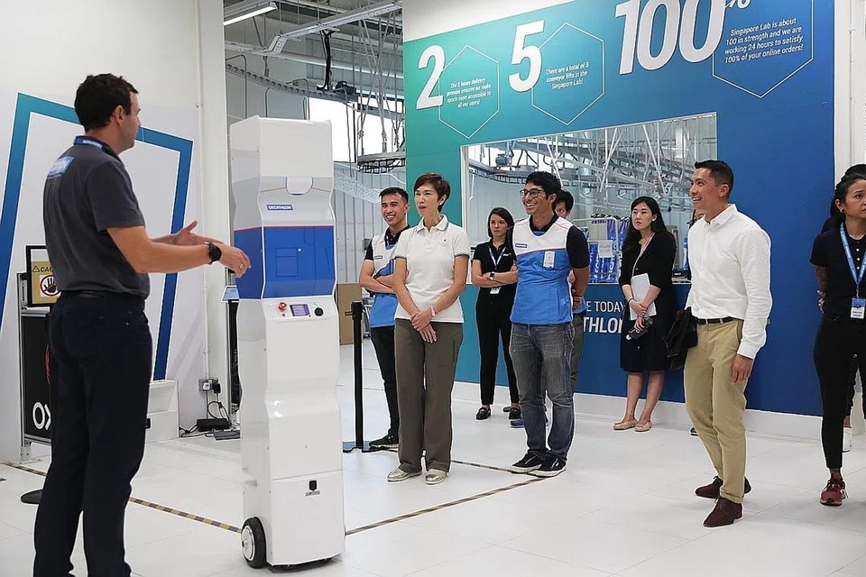 MANFAATKAN TEKNOLOGI: Semasa lawatannya ke cawangan Decathlon-Singapore Lab di Stadium Blvd baru-baru ini, Cik Josephine Teo (berbaju putih) berpeluang melihat bagaimana syarikat itu menggunakan Robot RFID untuk melakukan pemeriksaan inventori stok. - Foto BH oleh KELVIIN CHNG