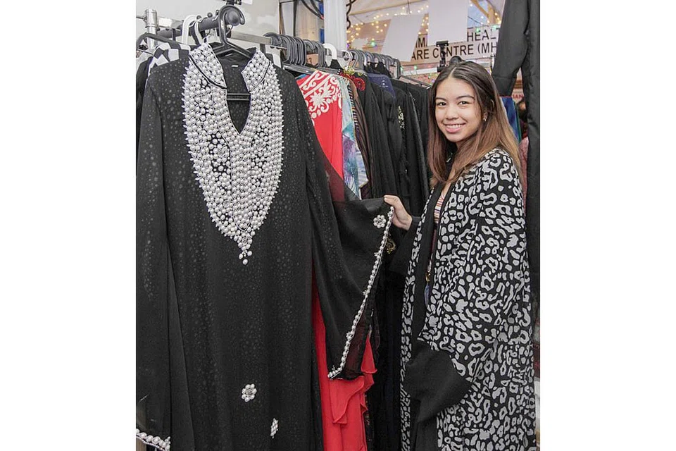 JADI TARIKAN: Cik Alyaa Naeem, 17 tahun, membantu di gerai keluarganya di Bazar Raya Utara menjual pelbagai abaya dan kelengkapan lain. - Foto BH oleh IQBAL FAISAL