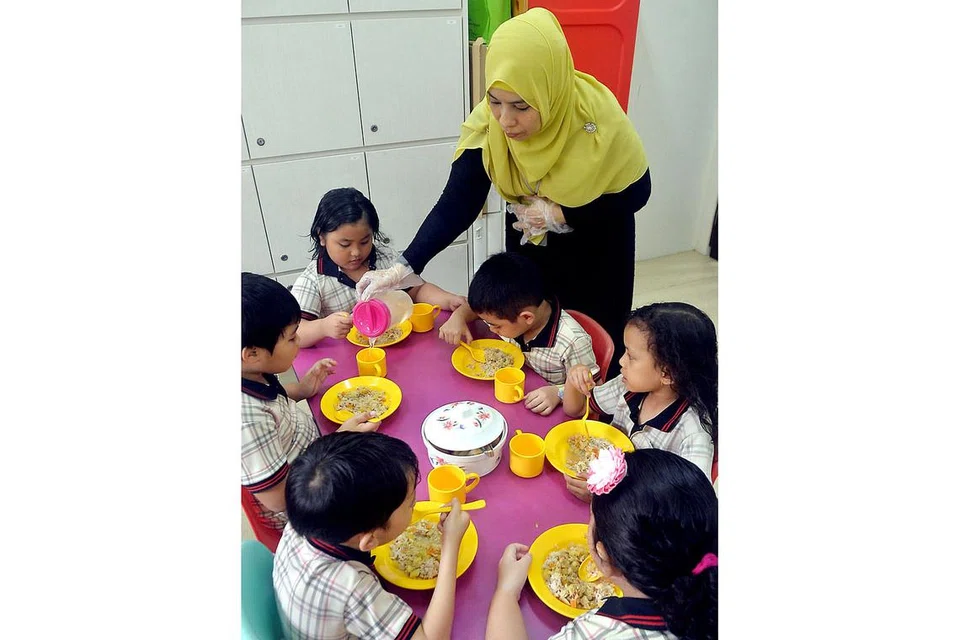 SAJIAN BERKHASIAT: Kanak-kanak di Pusat Pembangunan Kanak-Kanak PPIS Sembawang disajikan dengan hidangan makanan nasi ayam yang menggunakan campuran nasi putih dan beras ceruh. - Foto KHALID BABA